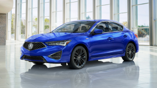 Front view of a blue Acura ILX in front of a building.